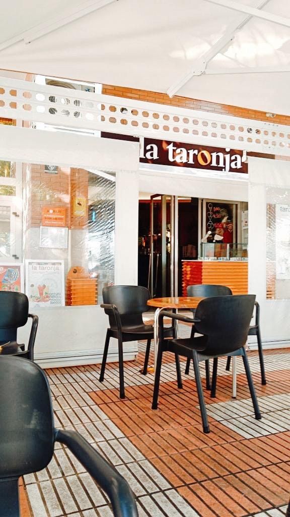 Mesas de la terraza a pleno día, bajo el toldo y frente al rótulo de La Taronja